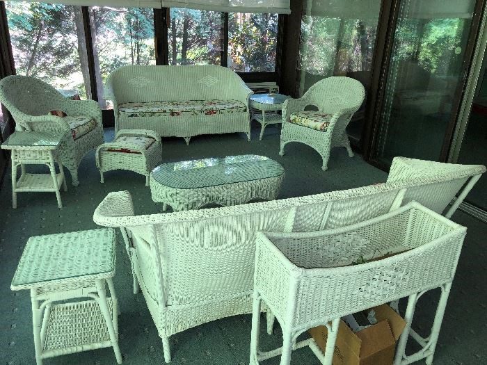 A room with many white wicker furniture and tables.