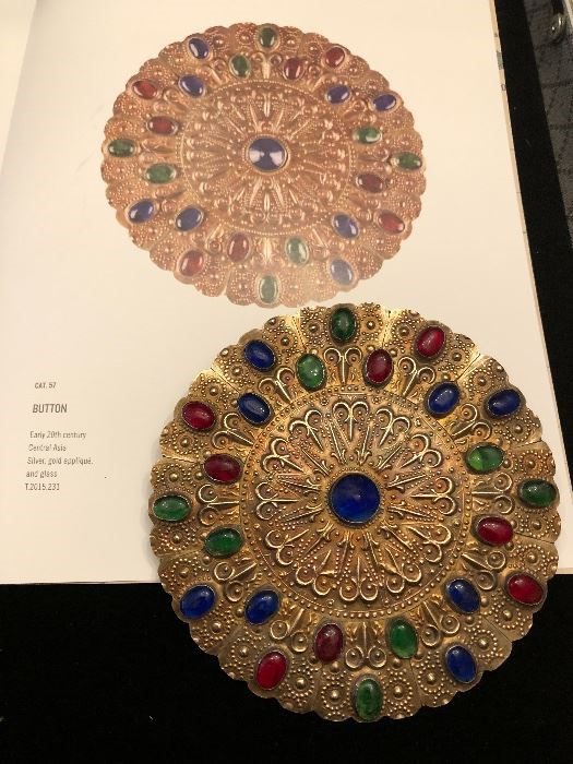 A book with two pictures of a gold and colored stone disc.